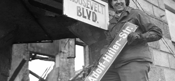 A man removes the sign for Adolf Hitler Street"