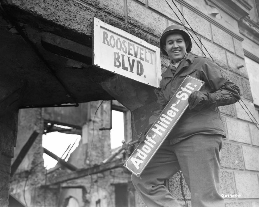 A man removes the sign for Adolf Hitler Street"